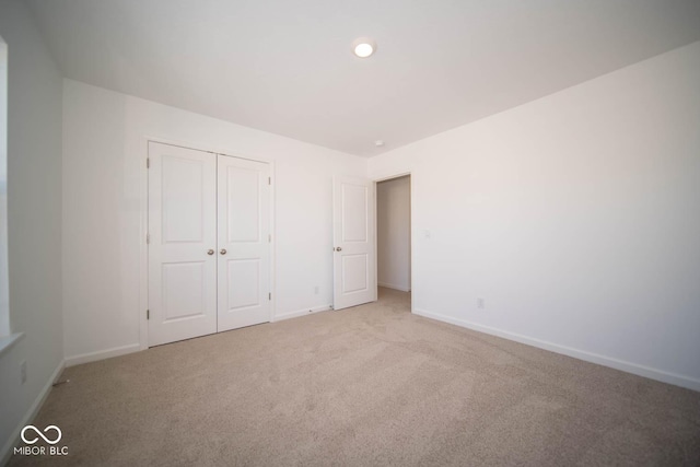 unfurnished bedroom featuring light carpet and a closet