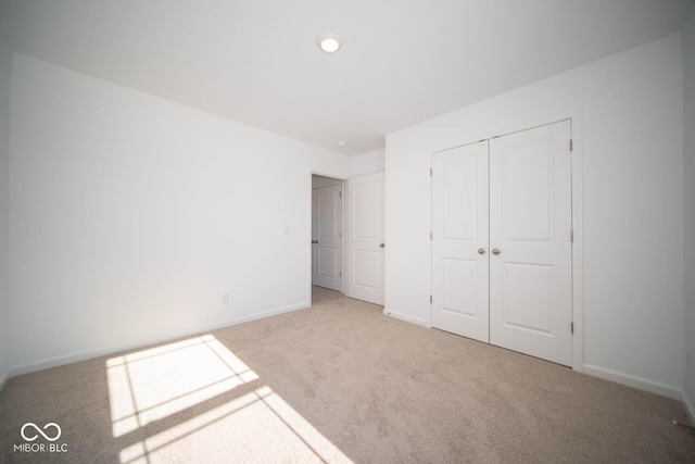 unfurnished bedroom with a closet and light carpet