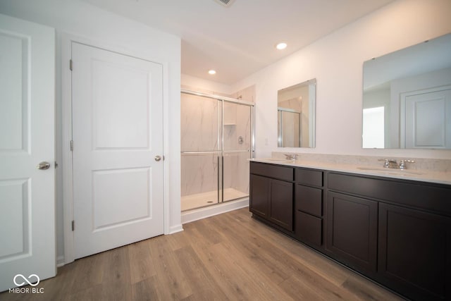 bathroom with an enclosed shower, vanity, and wood-type flooring