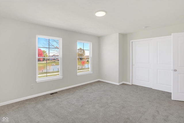 carpeted empty room featuring a water view