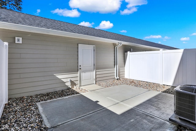 view of exterior entry featuring central air condition unit and a patio