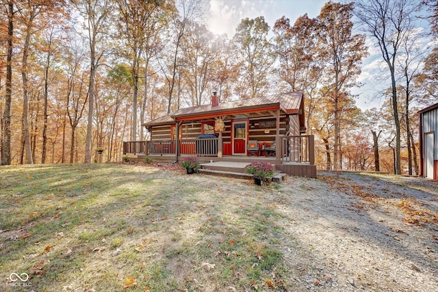 log cabin with a wooden deck and a front lawn