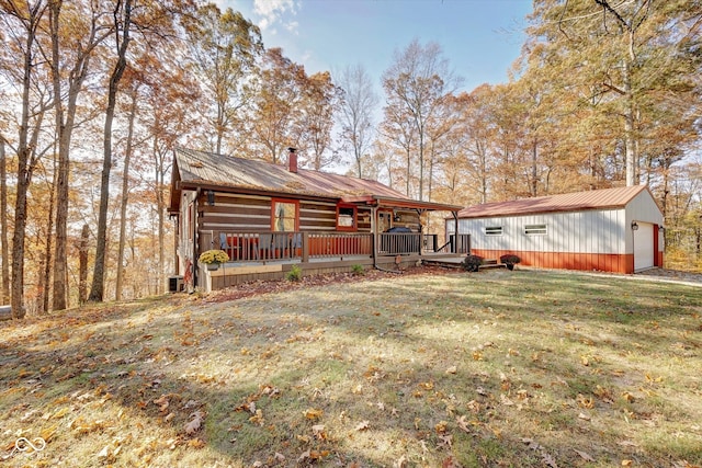 rear view of house featuring an outdoor structure, a garage, a deck, and a lawn