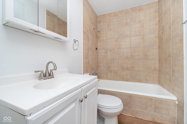 full bathroom with toilet, tiled shower / bath, and vanity