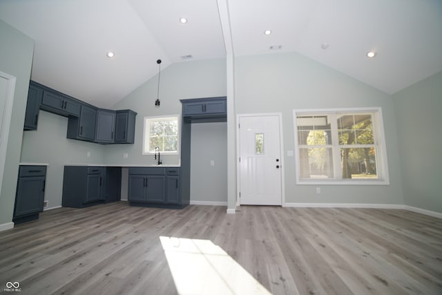 kitchen with light hardwood / wood-style flooring, high vaulted ceiling, and sink