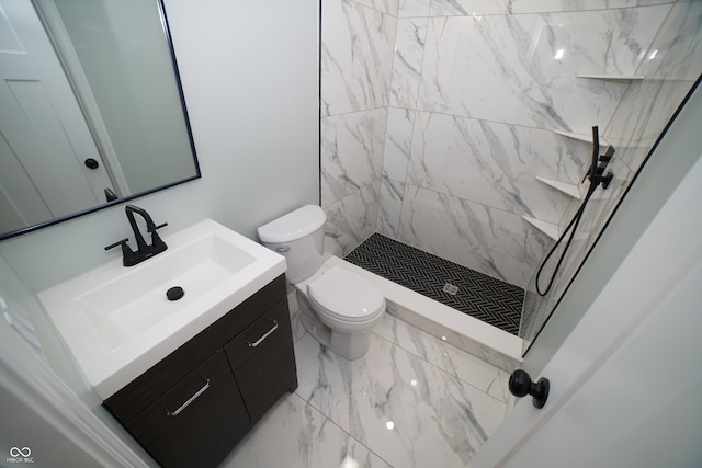 bathroom with vanity, a tile shower, and toilet