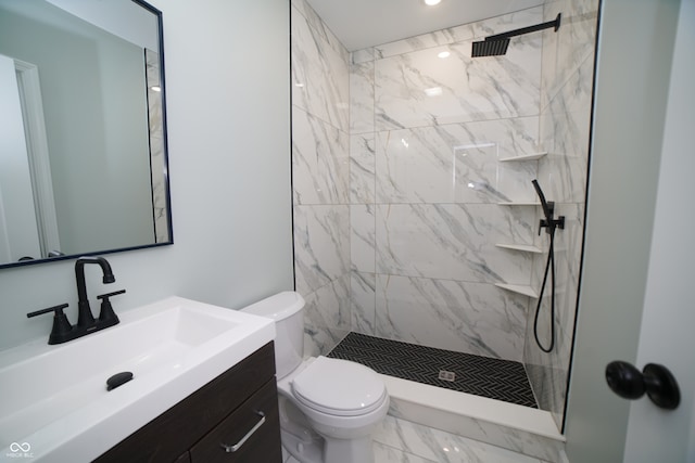 bathroom with vanity, toilet, and tiled shower