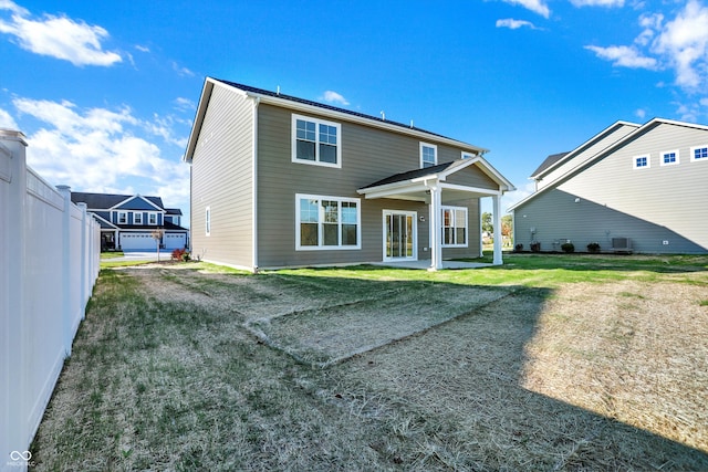 rear view of property featuring a garage and a lawn