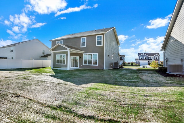 rear view of house with central AC unit and a lawn