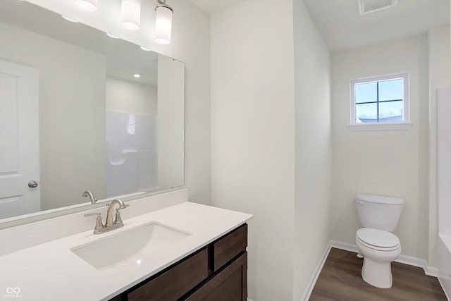 bathroom featuring a tub to relax in, vanity, hardwood / wood-style flooring, and toilet