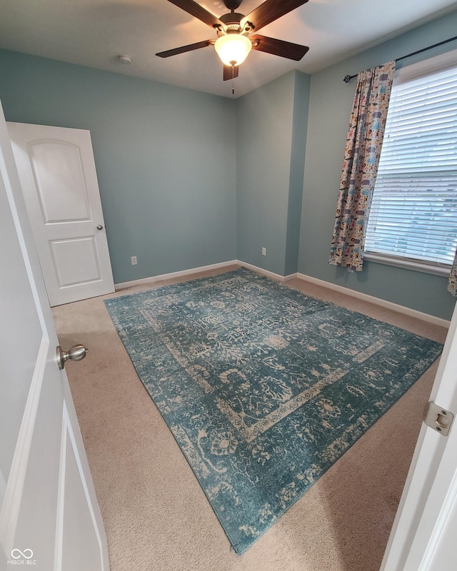 carpeted spare room featuring ceiling fan