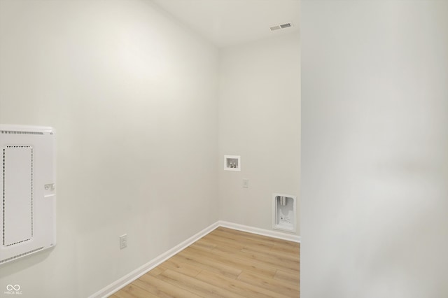 clothes washing area featuring heating unit, washer hookup, and light hardwood / wood-style flooring