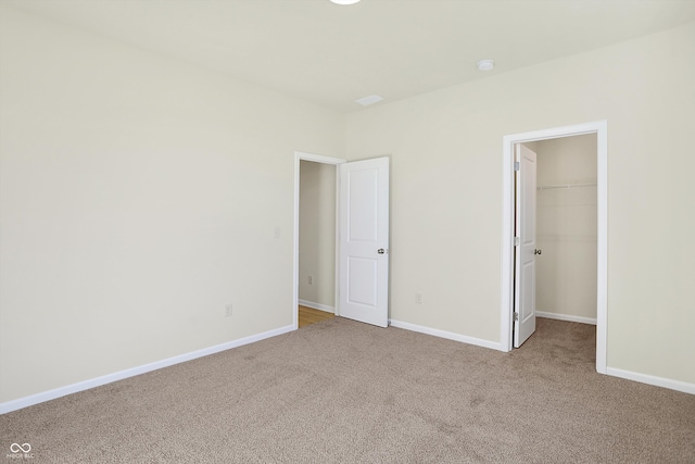 unfurnished bedroom featuring light colored carpet, a closet, and a walk in closet