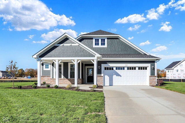 craftsman house featuring covered porch, a front yard, and a garage