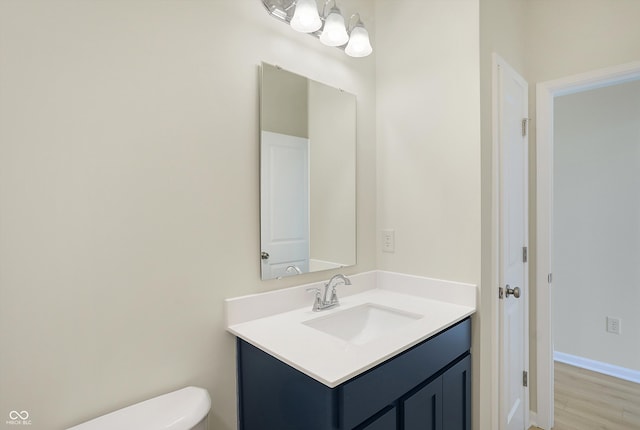 bathroom with toilet, vanity, and wood-type flooring