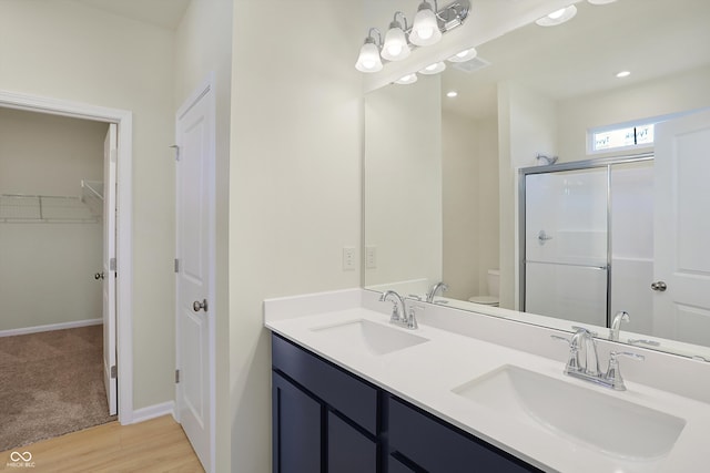 bathroom featuring a shower with door, vanity, hardwood / wood-style flooring, and toilet