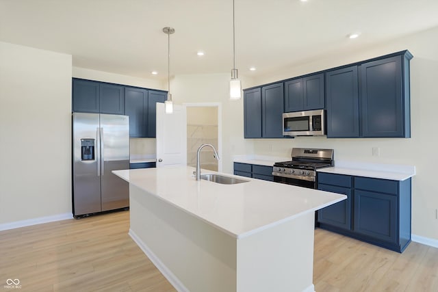 kitchen with light hardwood / wood-style floors, appliances with stainless steel finishes, sink, and a kitchen island with sink