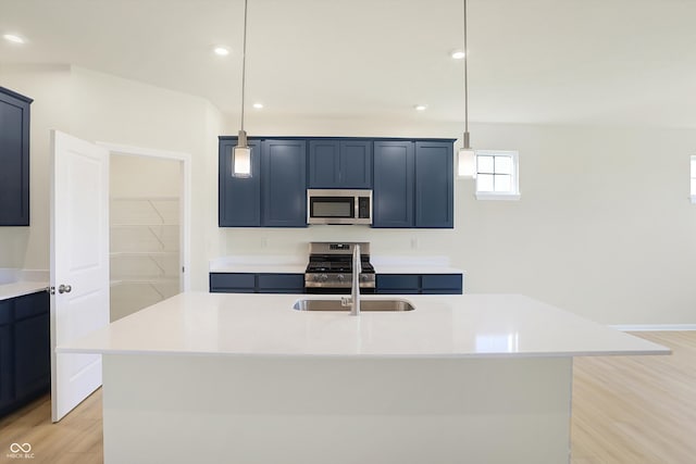 kitchen featuring decorative light fixtures, stainless steel appliances, a center island with sink, and sink