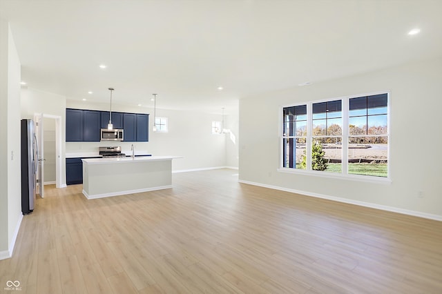 kitchen featuring a kitchen island with sink, sink, blue cabinets, appliances with stainless steel finishes, and light hardwood / wood-style floors