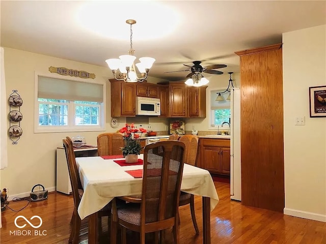 dining area featuring sink, dark hardwood / wood-style floors, and ceiling fan with notable chandelier