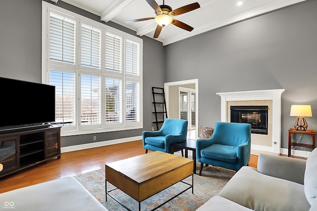 living area with light wood-style floors, beam ceiling, a fireplace, and baseboards