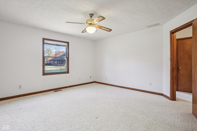 empty room featuring ceiling fan, a textured ceiling, baseboards, and light colored carpet