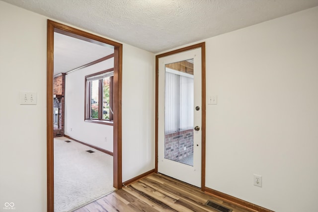 interior space with a textured ceiling and light hardwood / wood-style flooring