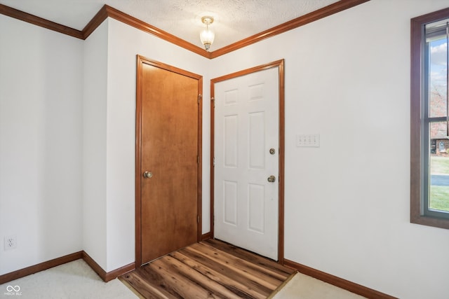 entryway with wood-type flooring, crown molding, a textured ceiling, and a wealth of natural light