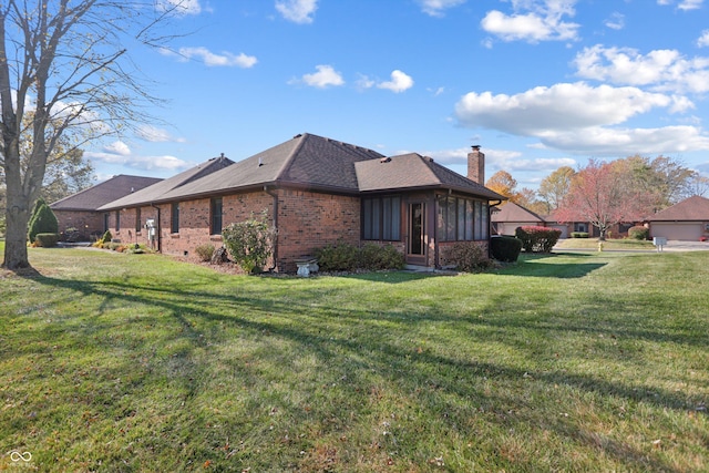 view of side of home featuring a chimney, a lawn, and brick siding