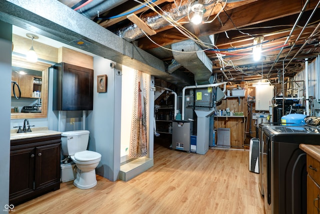 basement featuring separate washer and dryer, sink, light wood-type flooring, and heating unit