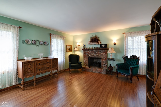 sitting room with hardwood / wood-style flooring and a brick fireplace