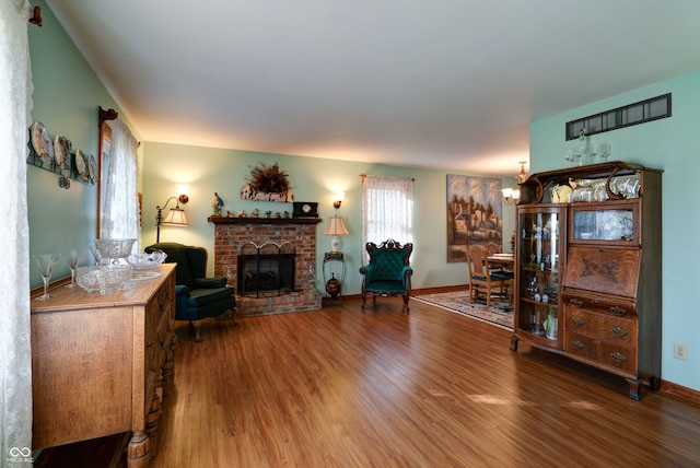 living room with a brick fireplace, hardwood / wood-style floors, and a chandelier