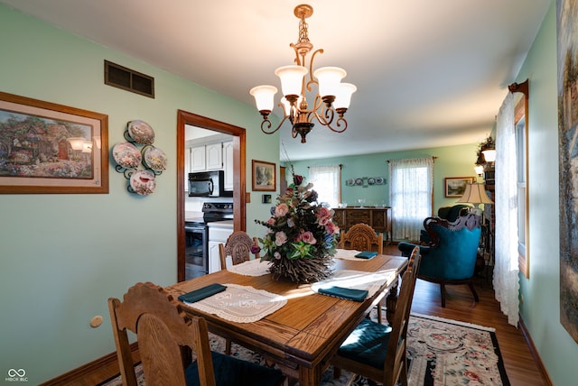 dining space with hardwood / wood-style flooring and a chandelier