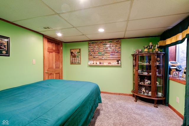 carpeted bedroom with a drop ceiling and crown molding