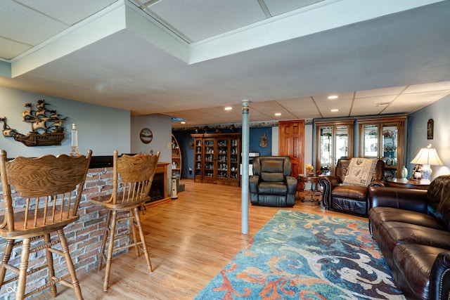 living room featuring a drop ceiling and light hardwood / wood-style flooring