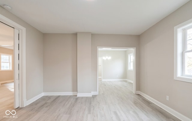 unfurnished room featuring a wealth of natural light, a chandelier, and light hardwood / wood-style floors