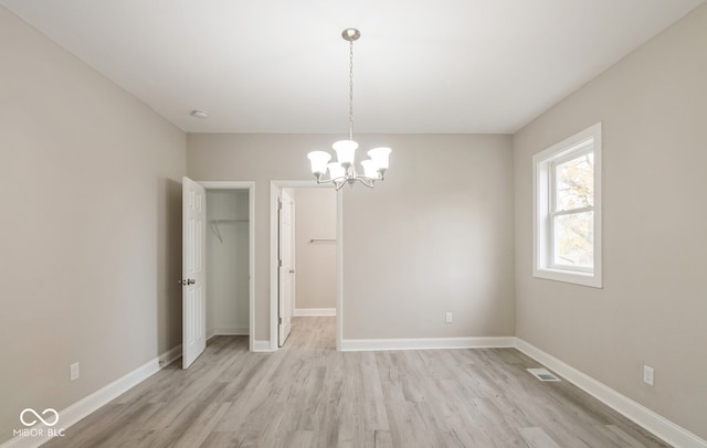 empty room with light hardwood / wood-style flooring and a chandelier