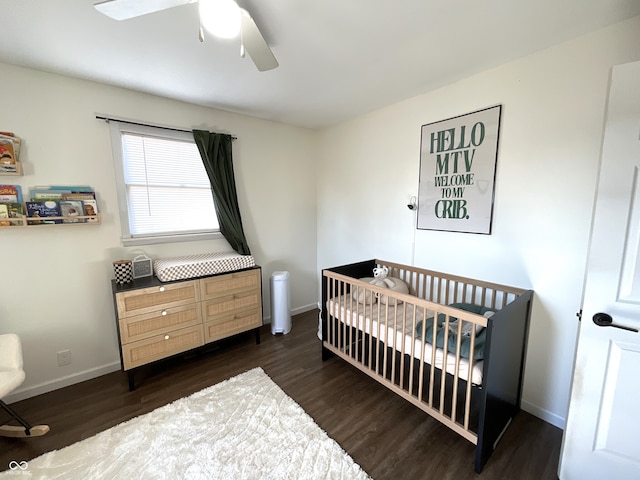 bedroom with ceiling fan, dark hardwood / wood-style flooring, and a nursery area