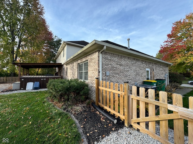 view of home's exterior featuring a lawn and a jacuzzi