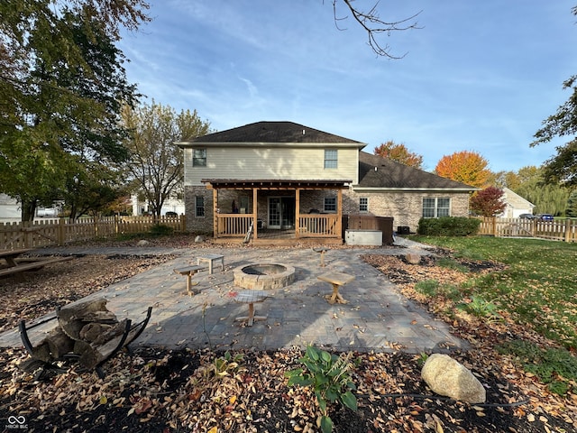 rear view of house with an outdoor fire pit, a hot tub, and a patio area