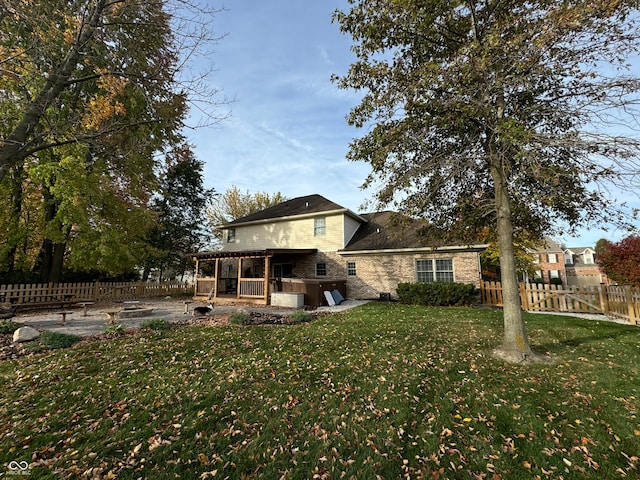 rear view of house with a yard, a patio area, and a hot tub