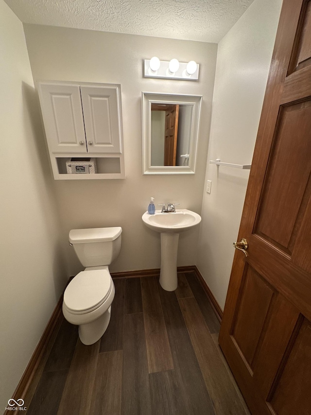 bathroom featuring hardwood / wood-style floors, sink, toilet, and a textured ceiling