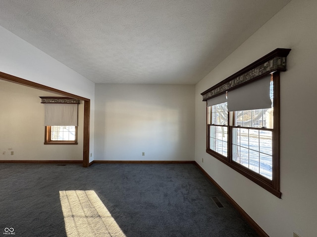 carpeted empty room featuring a textured ceiling