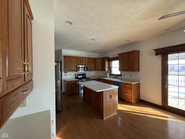 kitchen with sink, hardwood / wood-style flooring, a center island, stainless steel appliances, and a textured ceiling