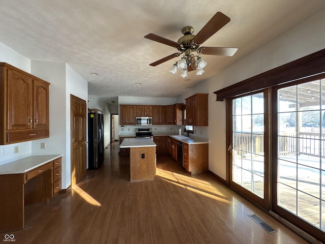 kitchen with sink, a center island, a textured ceiling, light hardwood / wood-style flooring, and black appliances