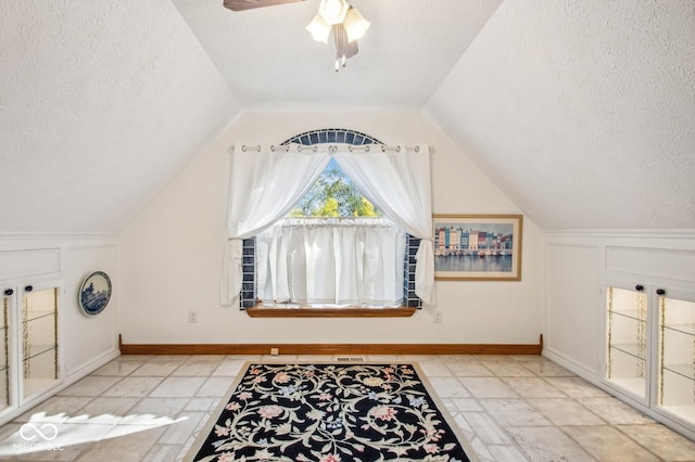 additional living space featuring a textured ceiling, vaulted ceiling, and ceiling fan