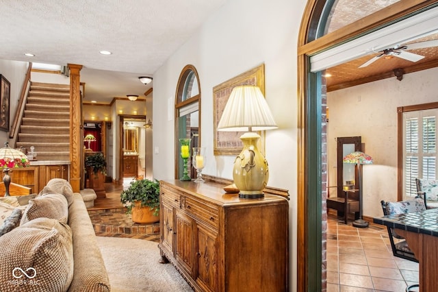 living room with light tile patterned floors, a textured ceiling, ceiling fan, and ornamental molding