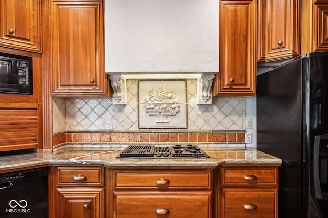 kitchen featuring decorative backsplash, light stone counters, and black appliances