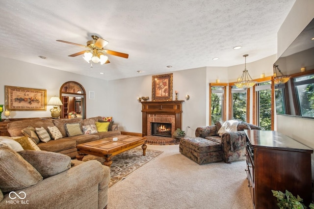 carpeted living room featuring a tile fireplace, a textured ceiling, and ceiling fan