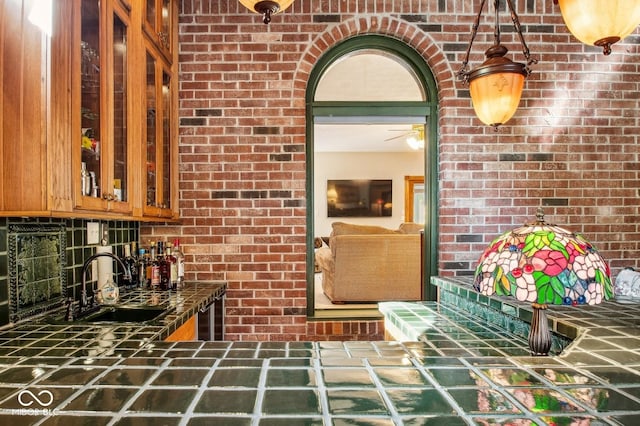 kitchen featuring decorative backsplash, sink, and brick wall